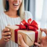 cheerful-young-woman-receiving-a-gift-from-her-boyfriend